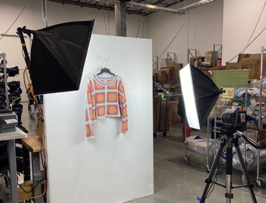 Sweater being photographed for an e-commerce listing in a secondhand warehouse