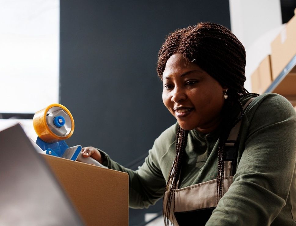 Woman taping up a box in a secondhand e-commerce warehouse